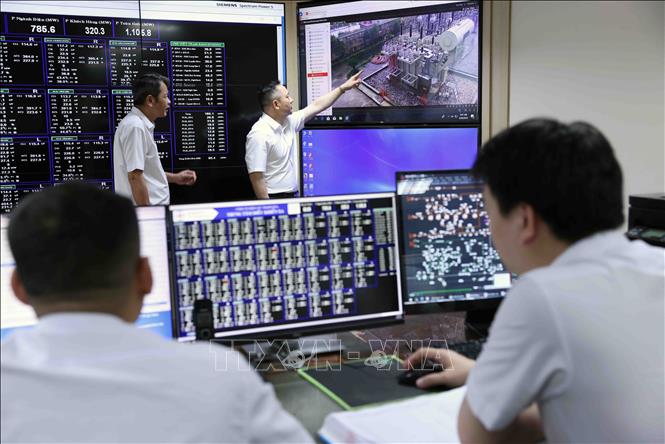 Ông Hoàng Hải, Giám đốc Công ty Điện lực Thanh Hoá (người đứng bên phải) kiểm tra công tác điều hành quản lý và vận hành hệ thống điện trong ca trực ở phòng điều hành Trung tâm ở Công ty Điện lực Thanh Hoá thuộc EVNNPC. Ảnh: Vũ Sinh – TTXVN