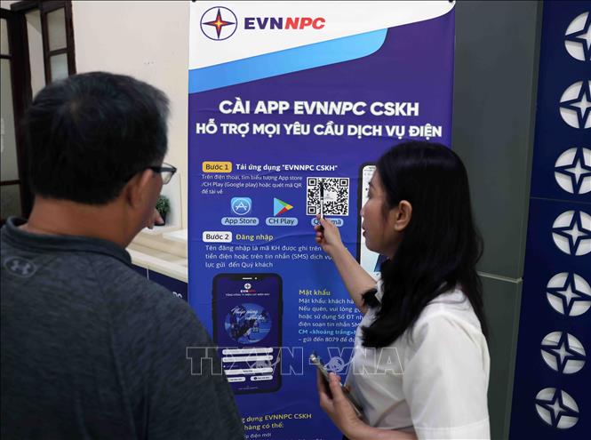 Nhân viên điện lực hướng dẫn người dân cài ứng dụng EVNNPC chăm sóc khách hàng, hỗ trợ mọi dịch vụ điện ở phòng giao dịch thành phố Thanh Hoá, tỉnh Thanh Hoá. Ảnh: Vũ Sinh – TTXVN