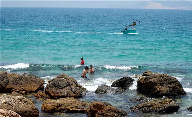 Du khách thích thú hòa mình vào làn nước biển trong xanh cạnh khu vực Mũi Vi Rồng. Ảnh: Lê Phước Ngọc - TTXVN