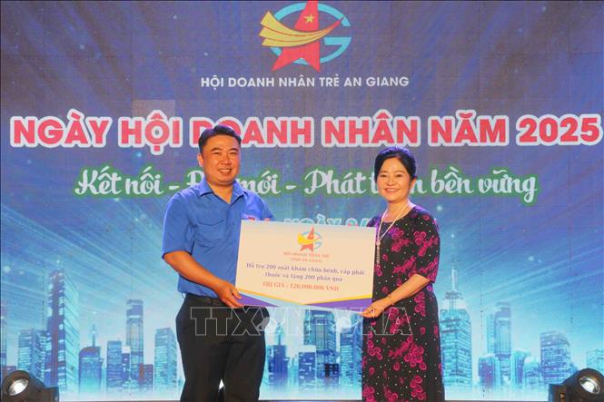 Bà Nguyễn Thị Mỹ Linh, Chủ tịch Hội Doanh nhân trẻ An Giang trao bảng tượng trưng hỗ trợ 200 suất khám chữa bệnh, cấp phát thuốc và tặng 200 phần quà cho bà con nhân dân có hoàn cảnh khó khăn trên địa bàn tỉnh An Giang. Ảnh: Công Mạo-TTXVN