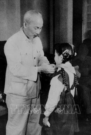 Chủ tịch Hồ Chí Minh quàng khăn đỏ cho đại biểu thiếu nhi Thủ đô đến chúc mừng kỷ niệm 30 năm Ngày thành lập Đảng (1960). Ảnh: Tư liệu TTXVN