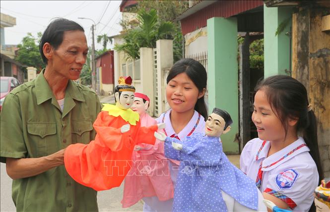 Nghệ nhân Nguyễn Văn Tươm hướng dẫn học sinh biểu diễn Rối. Ảnh: Minh Thu- TTXVN