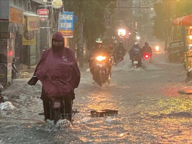 Người dân di chuyển trên đường Lê Văn Thọ (quận Gò Vấp) bị ngập do mưa lớn. Ảnh: TTXVN phát