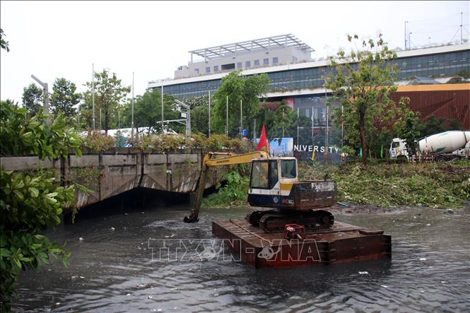 Các nhà thầu thi công nạo nét rạch Xuyên Tâm, đoạn phía trước Trường Đại học Văn Lang. Ảnh: Tiến Lực - TTXVN