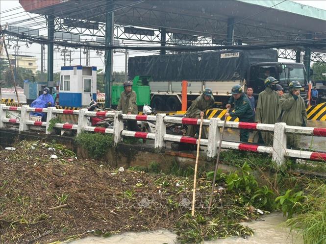 Các lực lượng được huy động để khẩn trương khơi thông dòng chảy, thu dọn lượng rác, cỏ dại và bèo tây đang gây tắc nghẽn tại các cửa cống, điểm giao của Suối Giữa. Ảnh: Dương Chí Tưởng-TTXVN