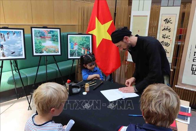 Ông đồ Jean-Sébastien Gill hướng dẫn các em nhỏ viết thư pháp. Ảnh: Hương Giang - PV TTXVN tại Bỉ