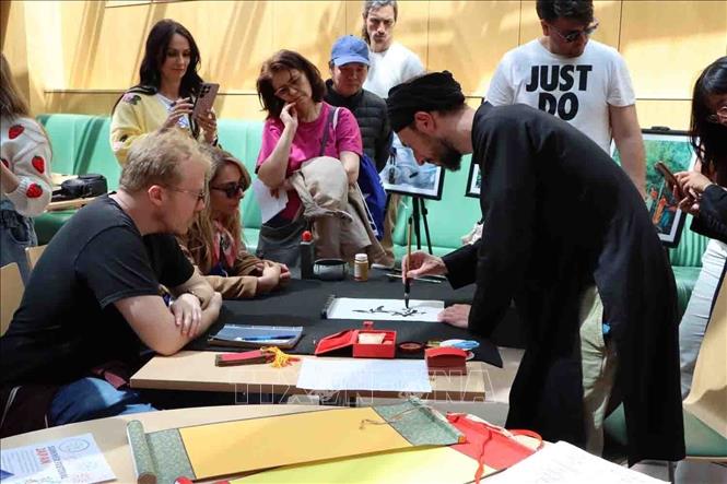 Du khách thích thú khám phá nghệ thuật thư pháp tại gian hàng Việt Nam. Ảnh: Hương Giang - PV TTXVN tại Bỉ