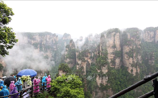 Trời mưa cũng không thể ngăn được dòng người tới thăm quan Khu danh lam thắng cảnh Vũ Lăng Nguyên. Ảnh: Quang Hưng - TTXVN tại Trung Quốc