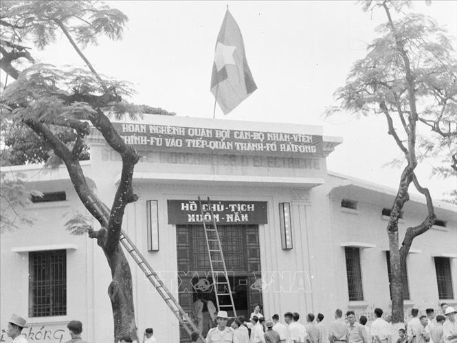 Công nhân nhà máy đèn khu Trung ương treo cờ, treo khẩu hiệu chào mừng bộ đội về tiếp quản. Ảnh: TTXVN