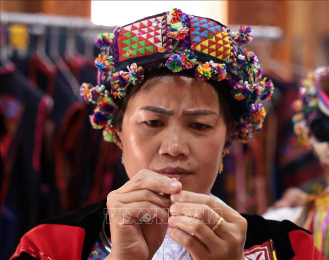 A Lo Lo woman skillfully embroiders floral patterns on traditional attire. VNA Photo: Trần Việt