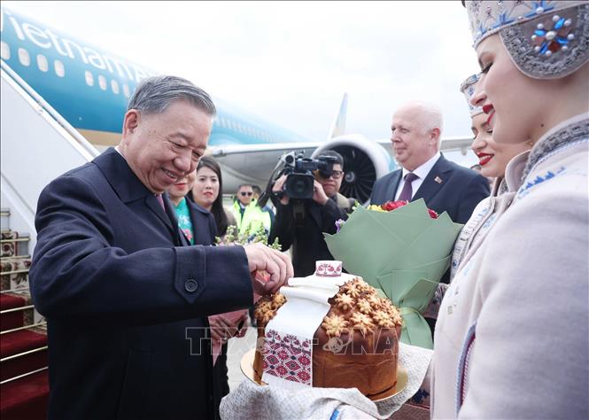 Thiếu nữ Belarus trong trang phục truyền thống trân trọng mời Tổng Bí thư Tô Lâm thưởng thức bánh mì và muối theo nghi thức đón khách quý của Belarus. Ảnh: Thống Nhất - TTXVN