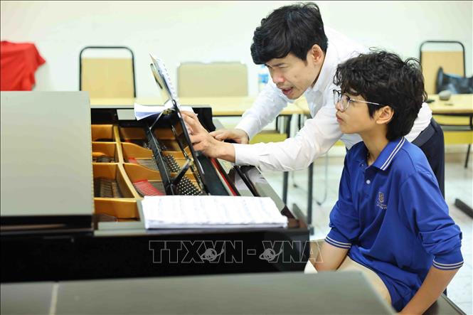 Cao Phú Quý (áo xanh) trong buổi luyện tập piano tại Học viện Âm nhạc Quốc gia Việt Nam. Ảnh: Minh Đức – TTXVN