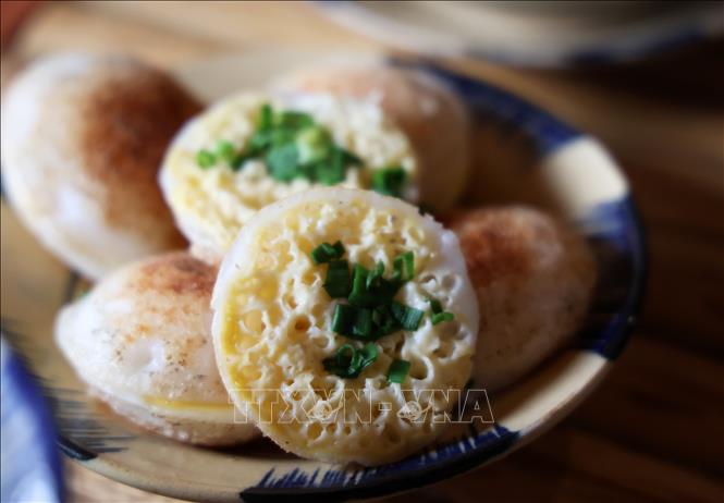 Bánh căn bày ra đĩa sẽ được úp lại thành một cặp và ở giữa quét thêm một lớp mỡ hành rất dậy mùi. Ảnh: Hồng Đạt - TTXVN 
