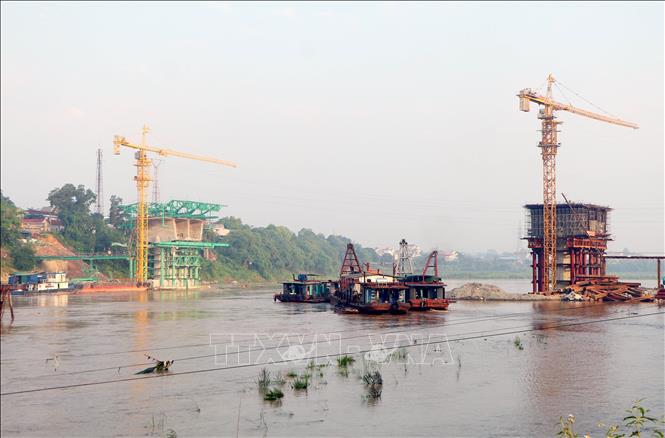 Tại khu vực thi công cầu Phong Châu mới, các đơn vị thi công vẫn đang làm việc khẩn trương, đảm bảo hoàn thành đúng tiến độ. Ảnh: Tạ Toàn – TTXVN