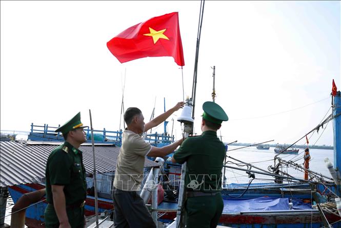 Bộ đội Biên phòng Quảng Trị tặng cờ tổ quốc cho chủ tàu cá Phan Văn Hoà ở tổ dân phố 3, thị trấn Cửa Việt trước khi ra khơi khai thác thuỷ sản. Ảnh: Vũ Sinh - TTXVN