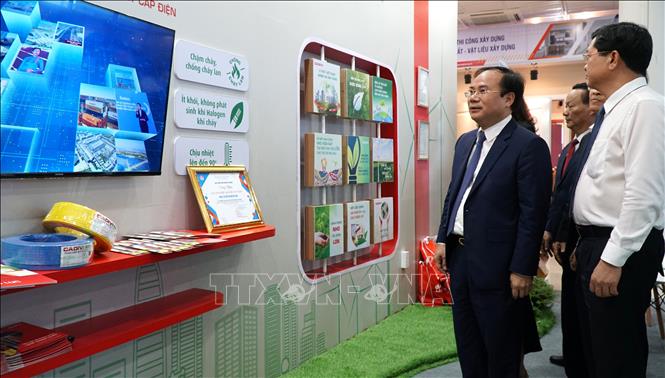 Thứ trưởng Bộ Xây dựng Nguyễn Văn Sinh (thứ hai, từ phải sang) nghe giới thiệu về các loại vật liệu xây dựng mới. Ảnh: Quốc Dũng - TTXVN