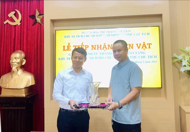Phó Giám đốc Khu Di tích Chủ tịch Hồ Chí Minh tại Phủ Chủ tịch Nguyễn Văn Dương tiếp nhận lọ hoa do gia đình ông Vũ Thanh Tùng trao tặng. Ảnh: Phương Lan - TTXVN