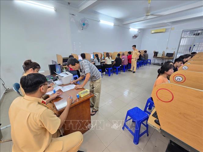 Công an hướng dẫn thí sinh làm thủ tục phần thi lý thuyết. Ảnh: Linh Sơn-TTXVN