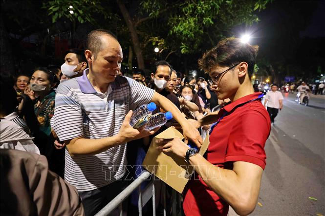 Phật tử các chùa hỗ trợ nước cho người dân xếp hàng trên phố Quán Sứ, để được chiêm bái xá lợi Đức Phật. Ảnh: Minh Đức – TTXVN