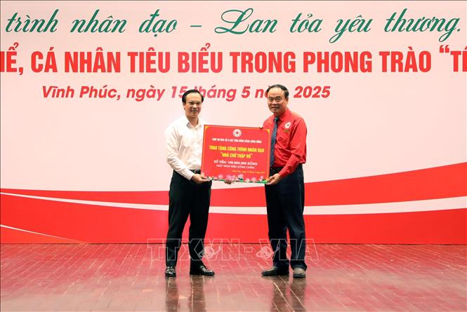 Đại diện Cụm thi đua số 2 các tỉnh Đồng bằng sông Hồng (trái) trao tặng công trình nhân đạo “Nhà Chữ thập đỏ” trị giá 100 triệu đồng cho Hội Chữ thập đỏ Vĩnh Phúc. Ảnh: Hoàng Hùng -TTXVN