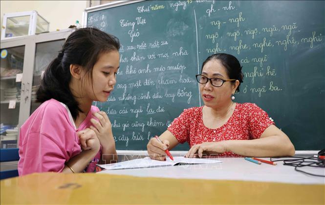 Cuối giờ học, bài tập viết của học sinh trong lớp sẽ được cô Thoa chấm điểm. Ảnh: Phương Hoa - TTXVN