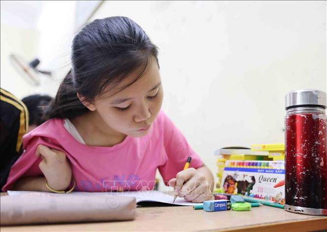 Em Vân (15 tuổi) dù chỉ hoạt động được tay trái những vẫn kiên nhẫn tô chữ cái. Ảnh: Phương Hoa - TTXVN