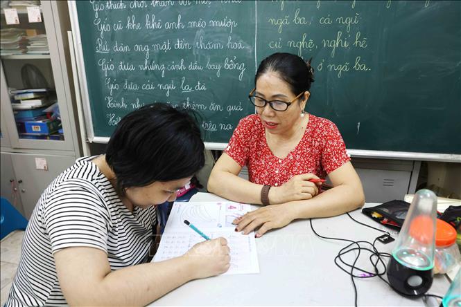 Cô Thoa hướng dẫn học sinh tô cho đúng chính tả. Ảnh: Phương Hoa - TTXVN