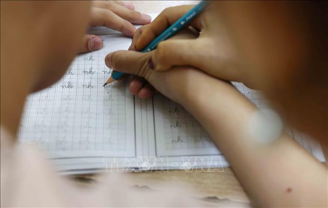 Cô Thoa hướng dẫn học sinh tô cho đúng chính tả. Ảnh: Phương Hoa - TTXVN