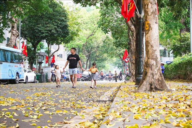 Families enjoy the beautiful leaf-changing season of Hanoi. VNA Photo: Khánh Hoà