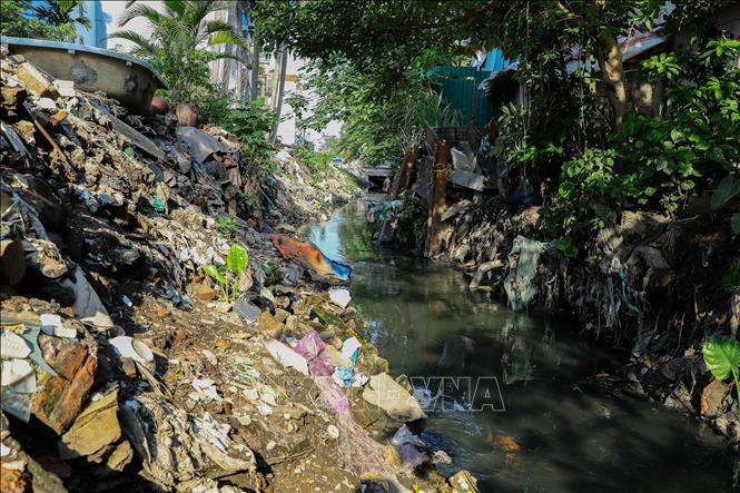 Rác thải xây dựng, nước thải chưa qua xử lý khiến con mương tại ngõ 61 Giang Văn Minh ô nhiễm nghiêm trọng ảnh hưởng đến cuộc sống của người dân (đoạn mương này kết nối với cống ngầm Phan Kế Bính). Ảnh: Lê Đông - TTXVN