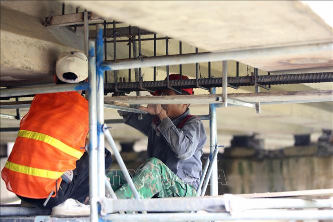 Công nhân thi công phần cốt thép tại vị trí dưới dầm cầu. Ảnh: Hữu Quyết - TTXVN