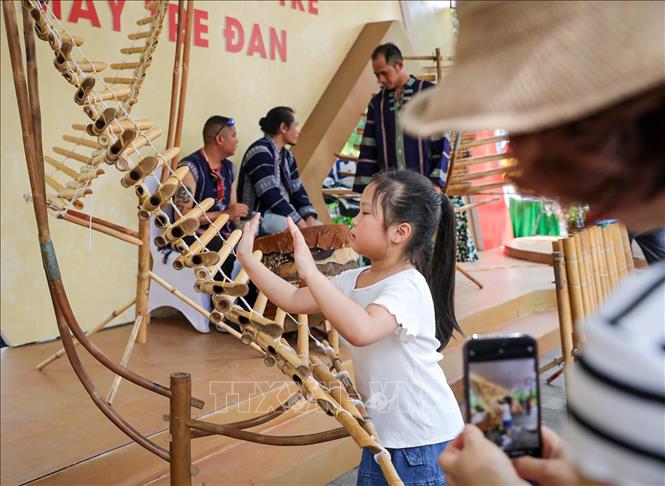 Nhạc cụ truyền thống của vùng Tây Nguyên thu hút một em nhỏ tìm hiểu. Ảnh: Khánh Hoà - TTXVN