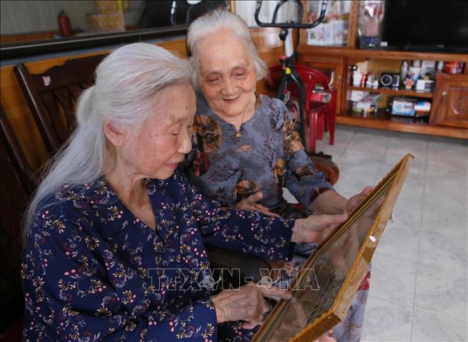 Bà Vũ Thị Bích Liên (bên trái) cùng với người bạn xem lại tấm ảnh đã chụp trong lúc đang làm việc tại Nhà máy Dệt Nam Định. Ảnh: Công Luật - TTXVN