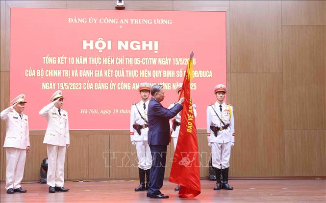 Tổng Bí thư Tô Lâm gắn huy hiệu “Anh hùng lực lượng vũ trang nhân dân” lên cờ truyền thống của Cục An ninh mạng và phòng, chống tội phạm sử dụng công nghệ cao, Bộ Công an. Ảnh: Phạm Kiên - TTXVN
