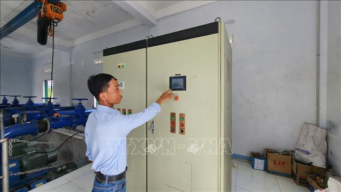 Cán bộ kỹ thuật điều tiết nước ở trạm bơm xã Mỹ Tài. Ảnh: Sỹ Thắng-TTXVN