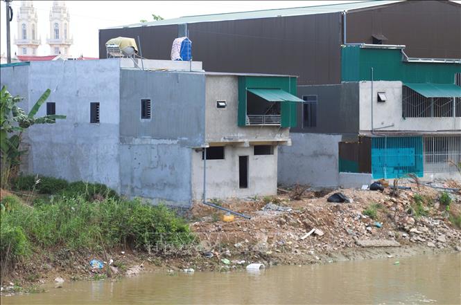 Nguy cơ sạt lở nhà cửa, công trình phụ, khu vực chăn nuôi do vị trí xây dựng nằm cheo leo sát hành lang kênh Vách Bắc là rất lớn. Ảnh: Xuân Tiến - TTXVN 