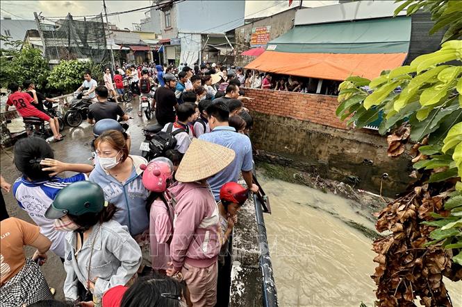 Nhiều người dân hiếu kỳ đứng xem lực lượng chức năng tìm kiếm tại đoạn suối nơi bé gái bị nước cuốn mất tích. Ảnh: Lê Xuân-TTXVN