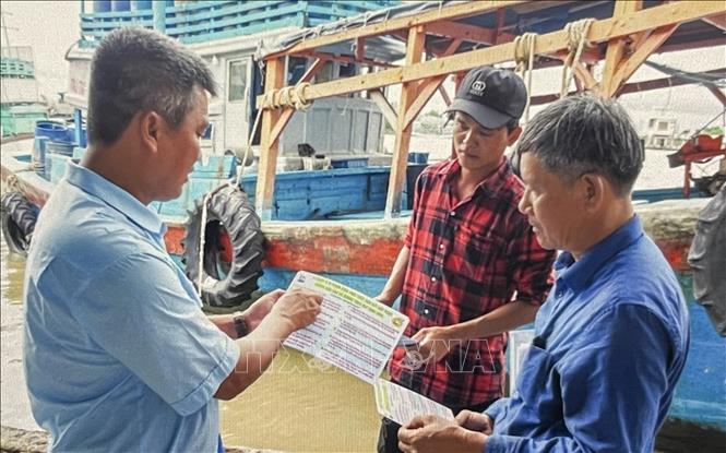 Nhân viên cảng cá Sông Đốc tuyên truyền quy định chống khai thác bất hợp pháp cho ngư dân trước khi tàu cập  cảng Sông Đốc. Ảnh: Hồng Nhung - TTXVN