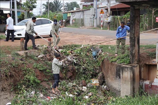 Nhân viên thủy nông thuộc Xí nghiệp Thủy lợi huyện Dương Minh Châu và người dân tổ chức dọn rác dưới lòng kênh. Ảnh: Thanh Tân - TTXVN