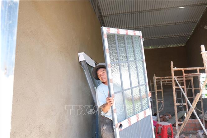 Ông K’Tos (thôn Kao Kuil, xã Đinh Lạc, huyện Di Linh) phụ giúp đội thợ xây dựng để giảm bớt tiền công làm nhà. Ảnh: Nguyễn Dũng – TTXVN 