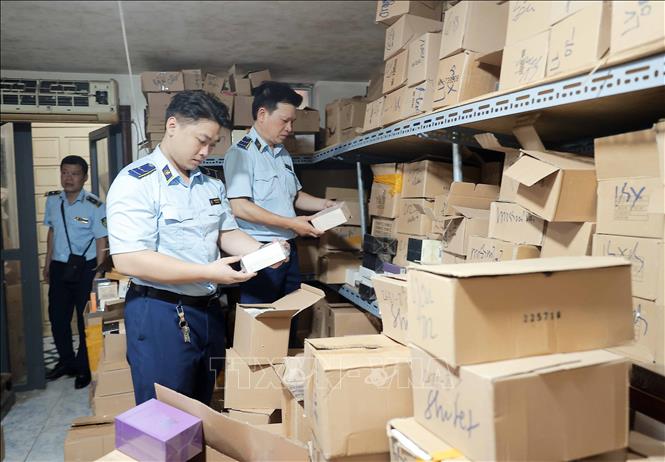 Lực lượng chức năng kiểm tra, thống kê số lượng tại kho hàng. Ảnh: Trần Việt - TTXVN