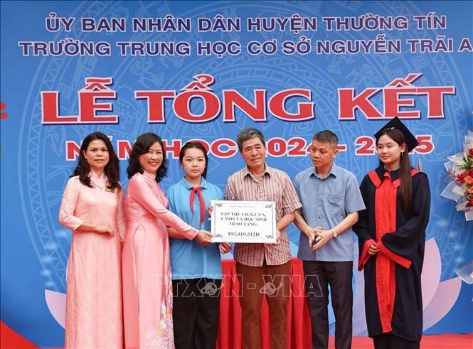 Ông nội và chị gái học sinh Tạ Quang An  (lớp 6A4, trường THCS Nguyễn Trãi) nhận tượng trưng số tiền hỗ trợ điều trị từ tập thể cán bộ, giáo viên nhân viên, phụ huynh và học sinh toàn trường THCS Nguyễn Trãi A (Thường Tín, Hà Nội). Ảnh: Thanh Tùng - TTXVN