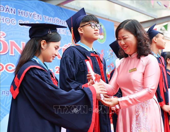 Cô Phạm Thị Ngọc Thúy, Bí thư chi bộ, Hiệu trưởng trường THCS Nguyễn Trãi A (Thường Tín, Hà Nội) trao giấy chứng nhận tốt nghiệp cho học sinh lớp 9. Ảnh: Thanh Tùng - TTXVN