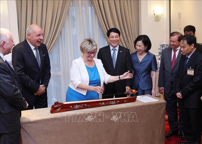 Hungarian President Sulyok Tamas's spouse experiences dan bau (one-string zither)  - a Vietnamese traditional musical instrument. VNA Photo: Lâm Khánh 