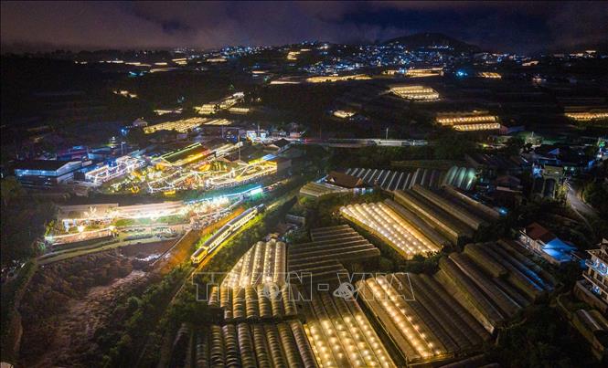 The train glides past brightly lit entertainment areas, vegetable gardens, and flower farms. VNA Photo: Hoàng Hiếu