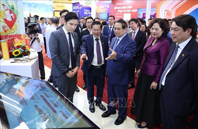 Thủ tướng Phạm Minh Chính tham quan trưng bày sản phẩm dịch vụ, ứng dụng chuyển đổi số trong hoạt động ngân hàng. Ảnh: Dương Giang-TTXVN
