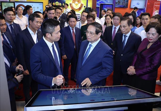Thủ tướng Phạm Minh Chính tham quan trưng bày sản phẩm dịch vụ, ứng dụng chuyển đổi số trong hoạt động ngân hàng. Ảnh: Dương Giang-TTXVN
