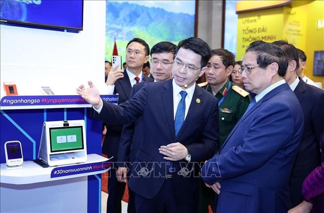 Thủ tướng Phạm Minh Chính tham quan trưng bày sản phẩm dịch vụ, ứng dụng chuyển đổi số trong hoạt động ngân hàng. Ảnh: Dương Giang-TTXVN
