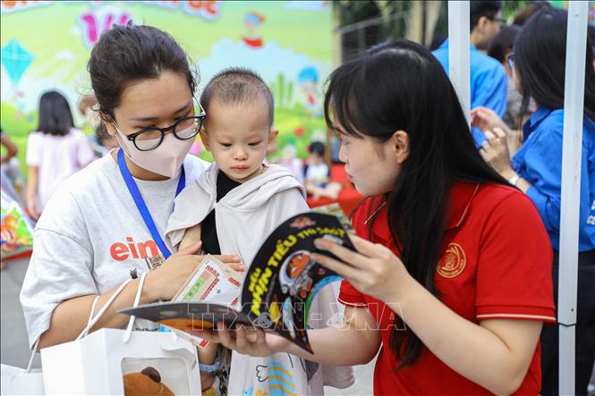 Tình nguyện viên giới thiệu sách cho người nhà và bệnh nhân nhi tham gia chương trình. Ảnh: Lê Đông - TTXVN