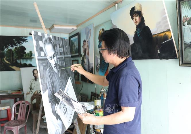 Painter Tran Hoa Binh and a portrait of President Ho Chi Minh. VNA Photo: Đức Phương 